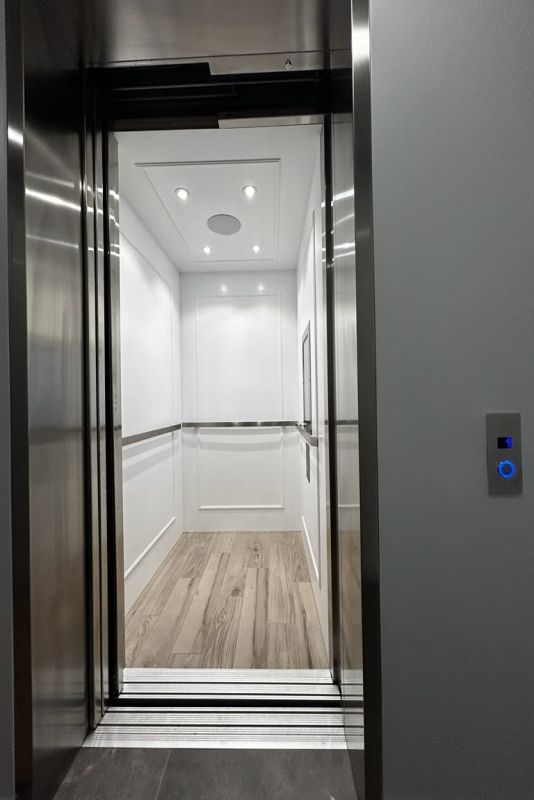 Residential home elevator interior in brushed metal and light finishes